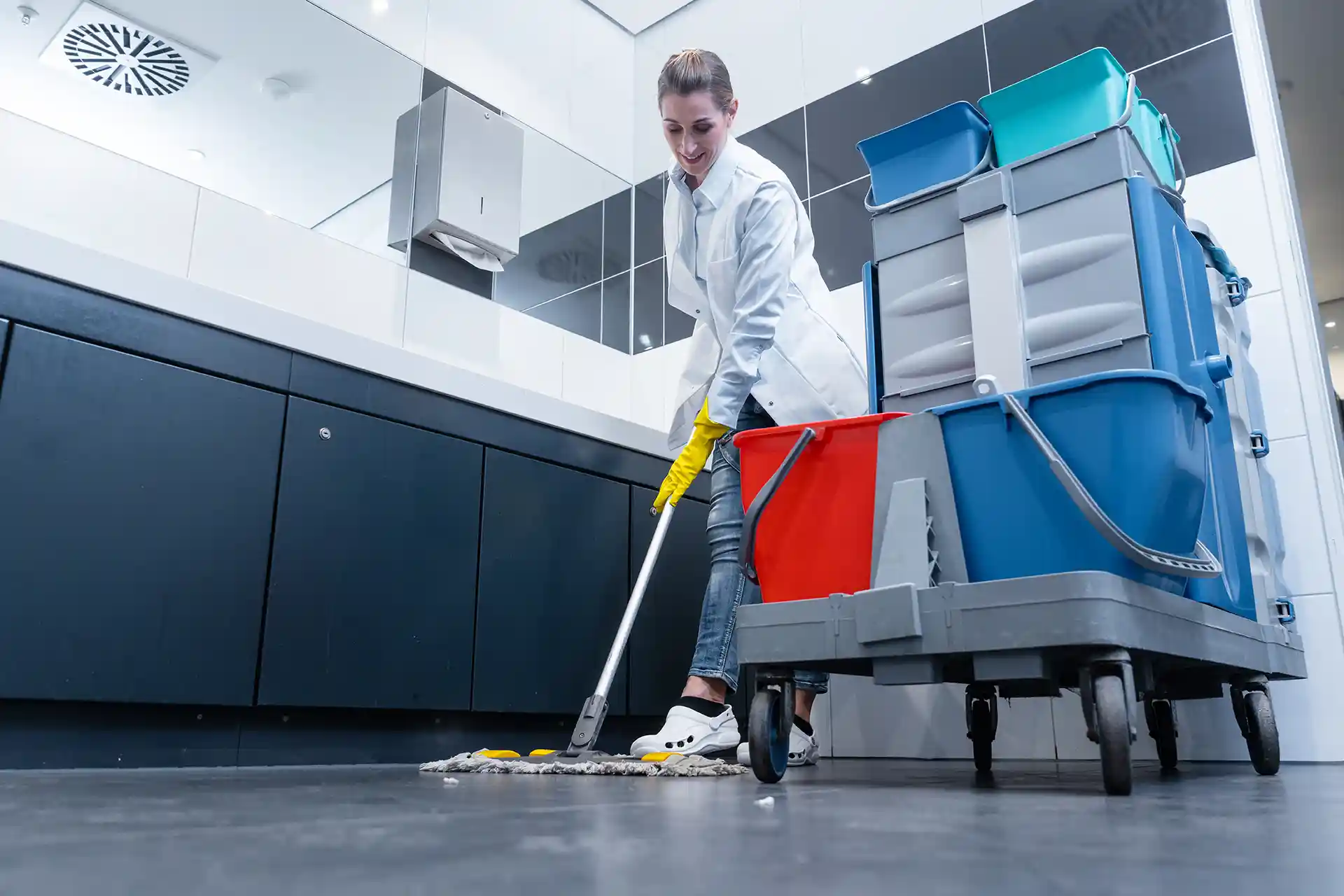 Janitor cleaning a bathroom with mop.
